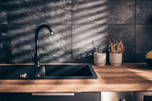 a black kitchen faucet with light wood tone countertop
